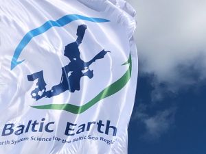 Die Fahne des internationalen Forschungsnetzwerks Baltic Earth im Wind flatternd vor blauem Himmel mit Wolken